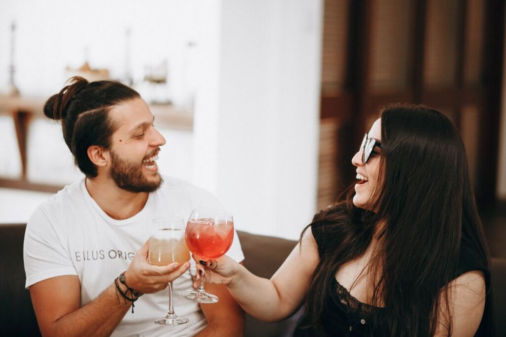 A man and woman joyfully toast with their drinks, symbolizing a shared celebration and connection.